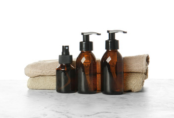 Shampoo and towels on table against white background