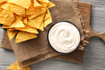 Tasty sour cream and potato chips on table