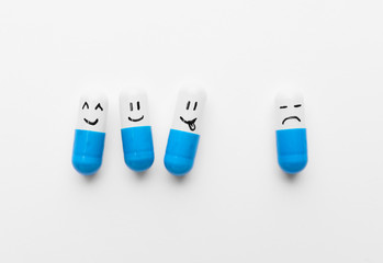 Pills with different drawn faces on white background