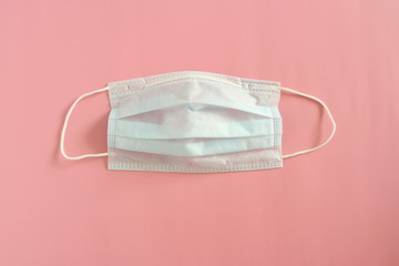 Medical disposable mask on a pink background. Coronovirus Outbreak Defense Concept.