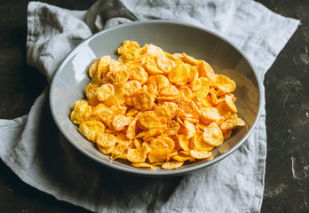 Tasty crispy corn flakes in bowl on the rustic background. Selective focus. Shallow depth of field.