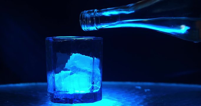 Drink being being into a glass on a glass table / bar counter top  in a bar / night club shot in slow motion