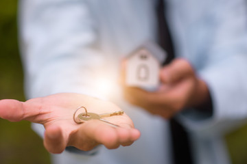 Close up salesman holding home key to business sale estate rent concept