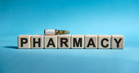 PHARMACY - text on cubes. Drug in ambula to reduce disease symptoms on a blue background