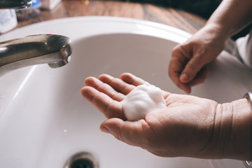 Asian elderly woman washing hand with foam soap.