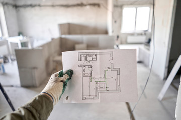 The construction worker hold in hands Architectural blueprints. Repair or construction of a new...