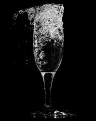 Splashes and drops of water in a glass are isolated on a black .