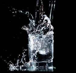 Splashes and drops of water in a glass are isolated on a black .