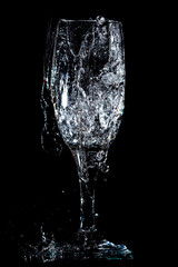 Splashes and drops of water in a glass are isolated on a black .