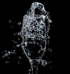 Splashes and drops of water in a glass are isolated on a black .