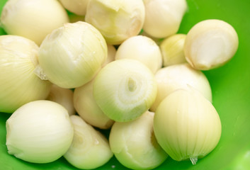 Fresh peeled onions in a green cup