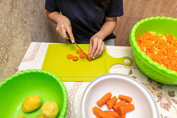 Girl cuts boiled carrots with a knife