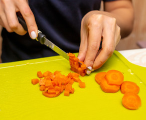 Girl cuts boiled carrots with a knife