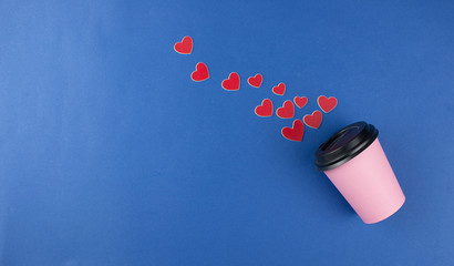 hot coffee in paper cup with red hearts on blue background