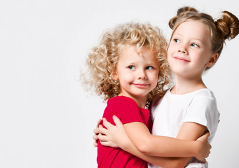Portrait of two happy kids girls sisters friends dancers in red and white t-shirts are close hugging each other