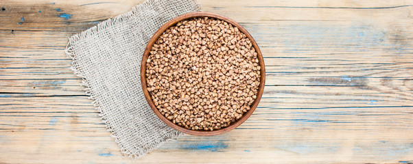 Buckwheat in a bowl in a wooden bowl with bagged in the background