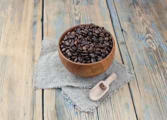 Dark coffee beans in a wooden bowl. Close up. Copy space.