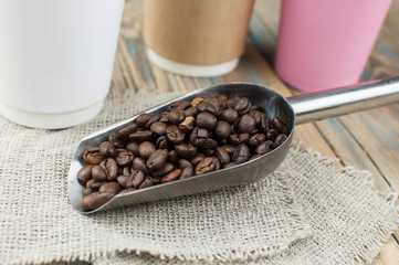 Disposable take-out mockup paper cups with coffee beans for morning espresso and brown bowl on wooden background