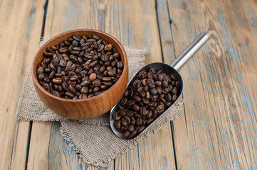 Dark coffee beans in a wooden bowl. Close up. Copy space.