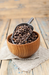 Dark coffee beans in a wooden bowl. Close up. Copy space.