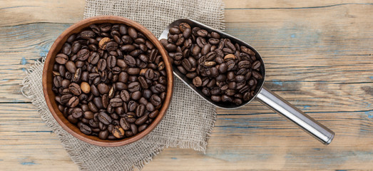 Dark coffee beans in a wooden bowl. Close up. Copy space.