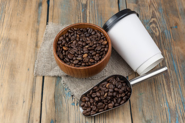 Disposable take-out mockup paper cups with coffee beans for morning espresso and brown bowl on wooden background