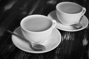 Two cups of coffee on a wooden table.