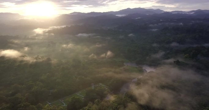 Pristine tropical rain forest of Ulu Temburong National Park. Sunrise rays,  low level clouds and meandering river. Aerial view