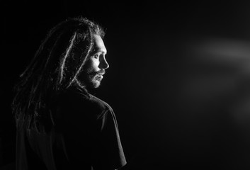 Male person with dreadlocks at dark background