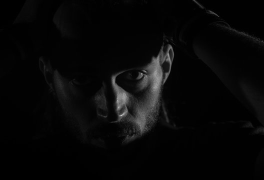 Dramatic portrait of male person looking at camera on dark background