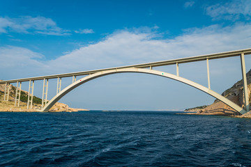 Fototapeta premium Bridge to the island Krk under blue sky on a sunny summer day. Krk is the big island of the Croatian coast of the Adriatic Sea. Travel landscape