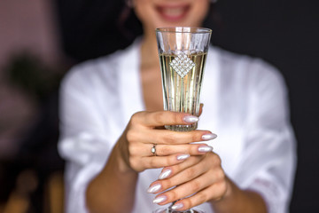 morning bride in lingerie holds a champagne glass and smiles. tender bride, boudoir photo shoot, bride in a dressing gown