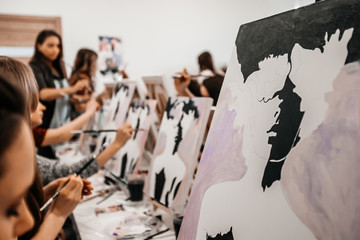 Young women paint with brushes on easels in art class. art school, creativity and people concept © Екатерина Рукосуева