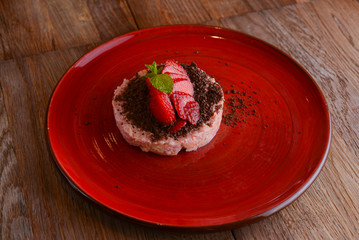 Fruit strawberry dessert with cream, strawberry delicious dessert served on red palte over rustic wooden table.