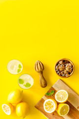 Fototapeta na wymiar Homemade lemonade in glasses near juicer and cut lemons on yellow background top-down copy space