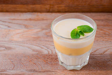 Fresh yogurt and lemon dessert. Fruit panna cotta in a glass over rustic wooden background. Copy space banner.