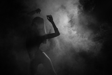 Female silhouette dancing in shadow and smoke