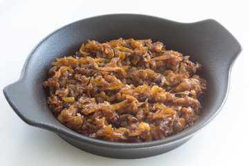 Close up caramelized onion on black plate on the white background