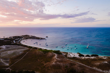 Aerial drone shot of a magical sunset over Rottnest Island, Perth, Western Australia. Geordie Bay below with luxury boats and yachts. 