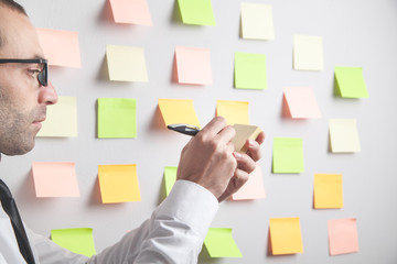 Businessman working with sticky notes in office.