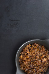 Top view of caramelized onion on black plate on the black background