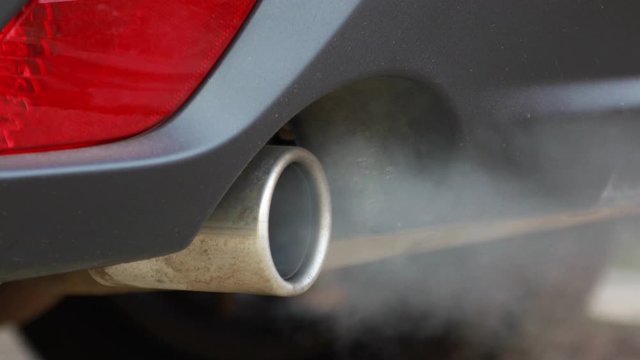 Smoke emissions fumes from car exhaust tailpipe causing air pollution and smog