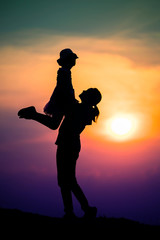 silhouette of a family with a happy mother playing with a girl in the sunset sky