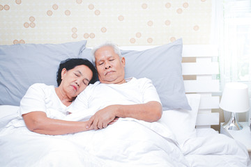 Asian elderly couple Sleep in bed in the bedroom. Senior health concepts, illness, retirement life. copy space