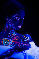 unusual modern shot of young caucasian woman with fluorescent body art, prints glows in ultra violet light. design, art, fluorescent, luminescence concept