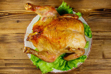 Baked whole chicken on a wooden table. Top view