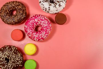 Tasty donuts and macaroons on pink background. Top view, copy space