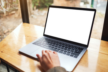 Mockup image of a woman using and touching on laptop computer touchpad with blank white desktop screen on wooden table