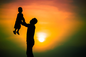 Fototapeta na wymiar silhouette of the family that the father is playing with the boy happily with the sunset sky