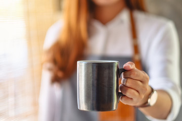 A waitress holding and serving a cup of hot coffee in cafe